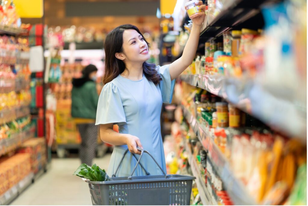 スーパーで備蓄用の食品を選ぶ女性