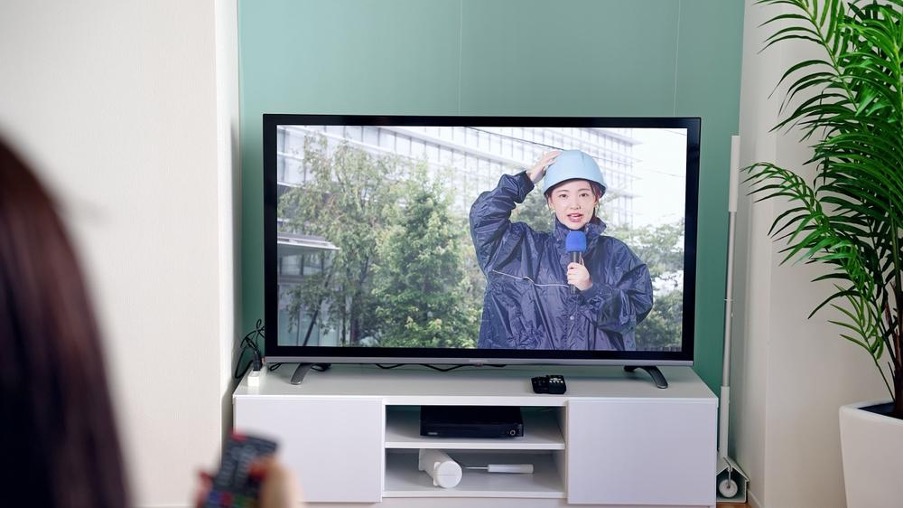 台風情報の中継を見る女性