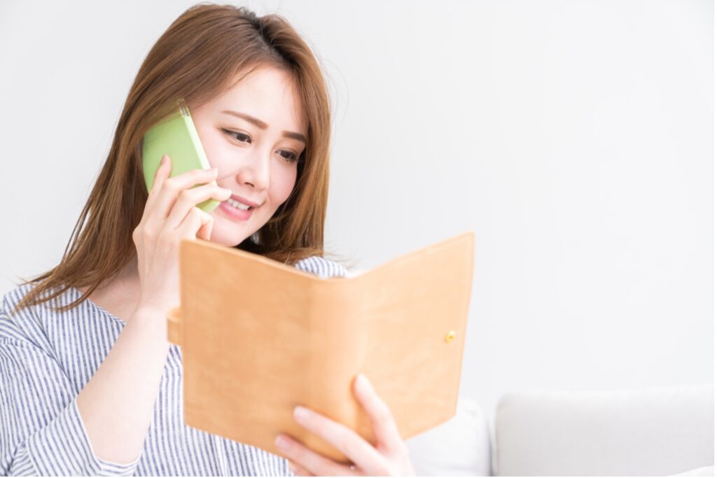 通話しながらメモを見る女性