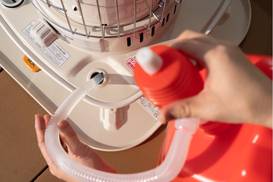 ストーブの給油口に灯油ポンプを差し込む人