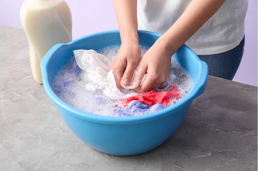 灯油のシミがついた服を揉み洗いする人