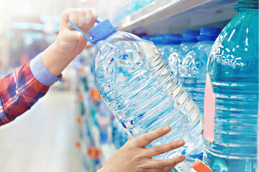 水の入ったペットボトルを棚から取る人